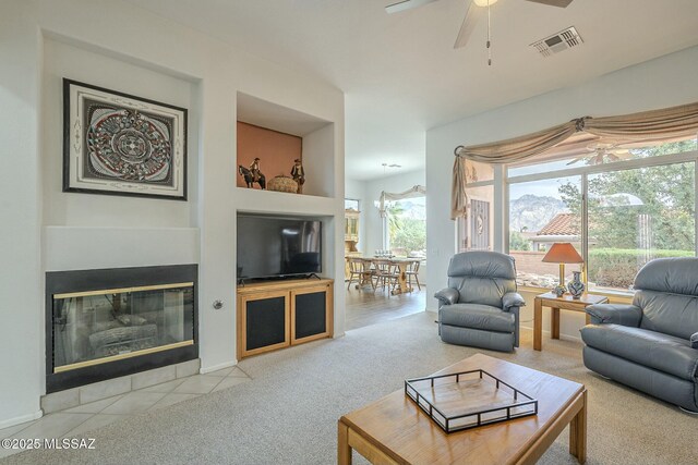 carpeted living room featuring a fireplace, visible vents, and a ceiling fan