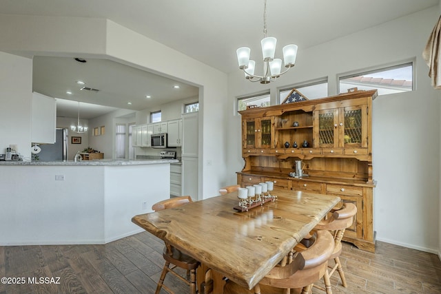 dining space featuring light wood-style floors, baseboards, visible vents, and a notable chandelier