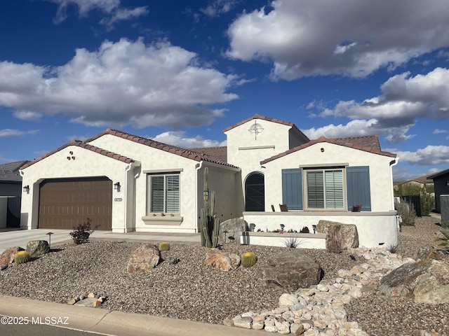 mediterranean / spanish home with stucco siding, driveway, a tile roof, and a garage