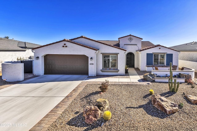 mediterranean / spanish home with concrete driveway, a tiled roof, a garage, and stucco siding