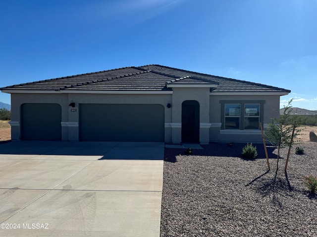 view of front of property with an attached garage, a tiled roof, concrete driveway, and stucco siding