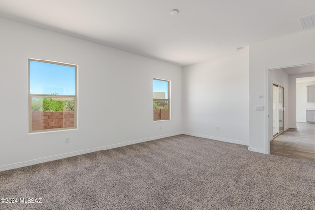 empty room featuring light carpet, visible vents, and baseboards