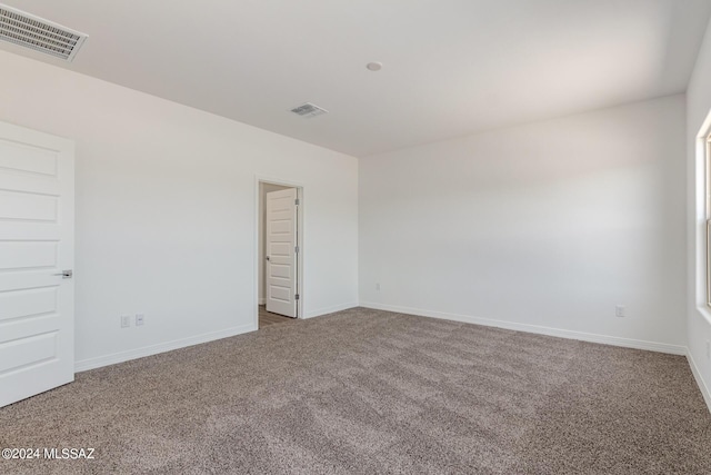 unfurnished room featuring carpet flooring, visible vents, and baseboards