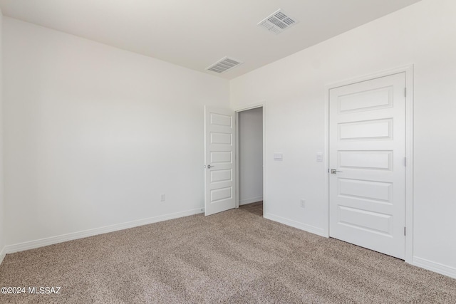 carpeted empty room with visible vents and baseboards