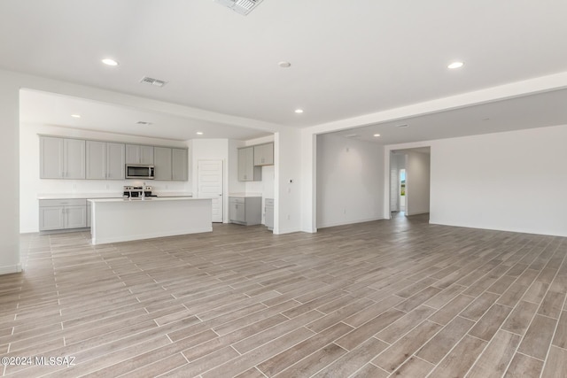 unfurnished living room with wood finish floors, visible vents, and recessed lighting