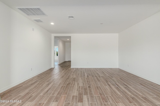 empty room featuring light wood finished floors, baseboards, and visible vents