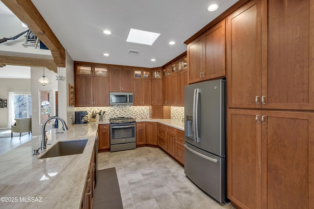 kitchen with visible vents, a sink, appliances with stainless steel finishes, brown cabinetry, and decorative backsplash