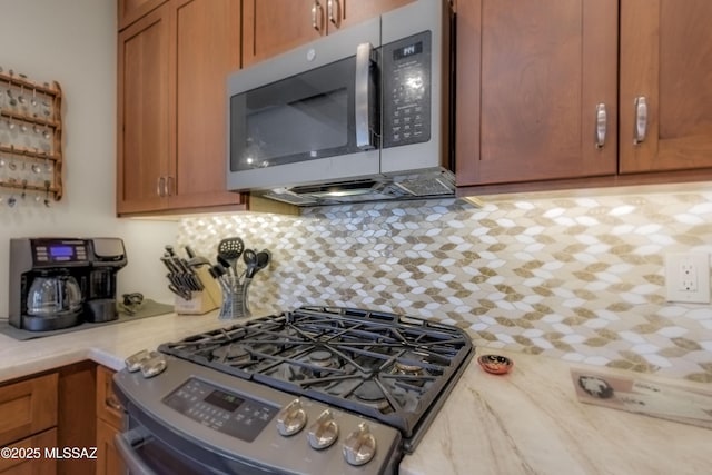 kitchen featuring decorative backsplash, brown cabinets, stainless steel appliances, and light countertops