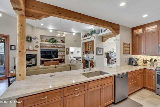 kitchen with light stone counters, beam ceiling, a peninsula, stainless steel appliances, and a sink