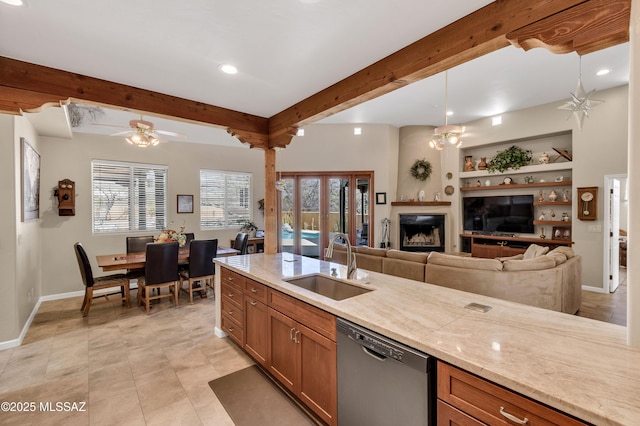 kitchen featuring beamed ceiling, stainless steel dishwasher, brown cabinetry, plenty of natural light, and a sink