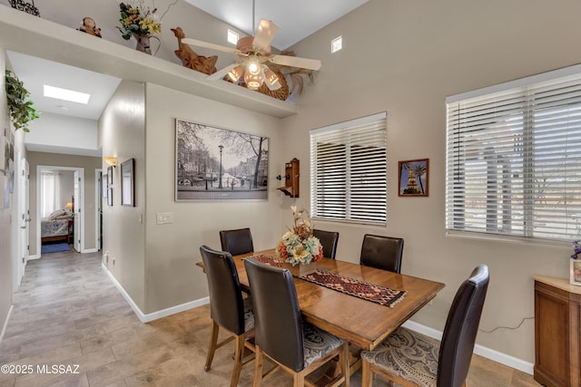 dining space featuring a skylight, baseboards, and ceiling fan