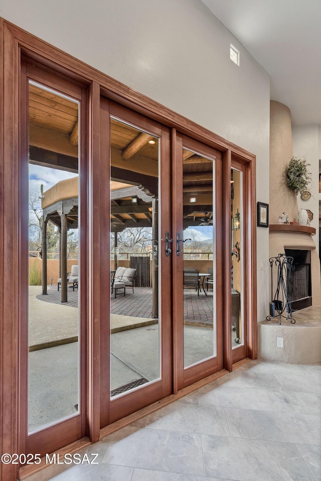 entryway with french doors and a fireplace with raised hearth