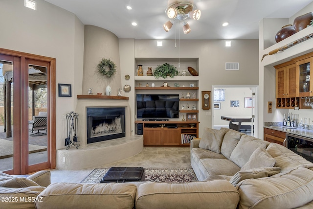 living room featuring visible vents, built in features, a high end fireplace, light colored carpet, and a dry bar