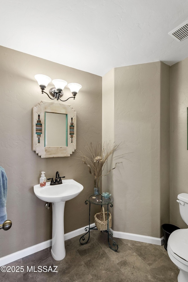 half bathroom featuring visible vents, baseboards, and toilet