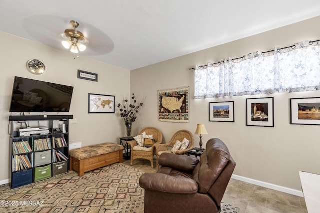 living area with a ceiling fan and baseboards