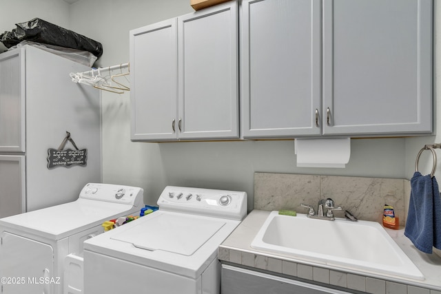 washroom with washer and dryer, cabinet space, and a sink