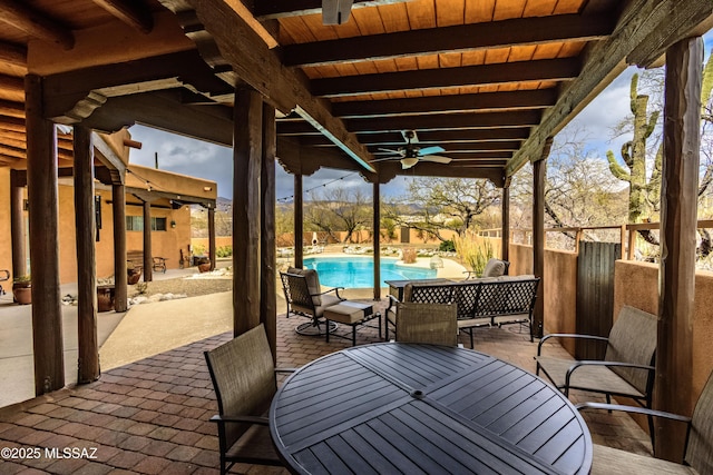 view of patio with outdoor dining space, a fenced in pool, and a ceiling fan