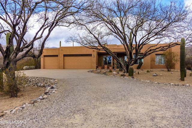 southwest-style home with an attached garage, driveway, and stucco siding