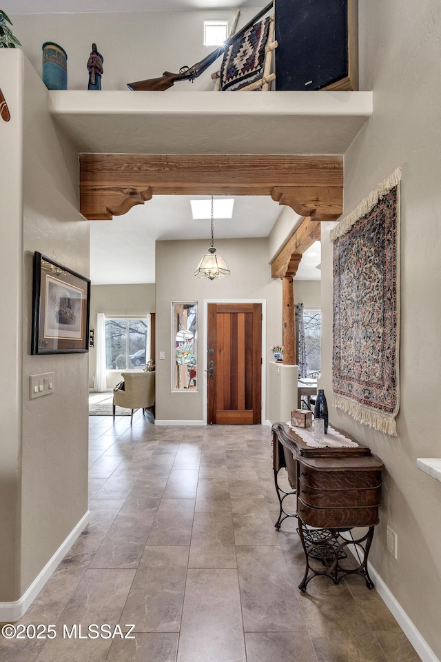 entrance foyer featuring ornate columns, beamed ceiling, a high ceiling, and baseboards