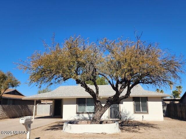 single story home with stucco siding, an attached carport, concrete driveway, and fence