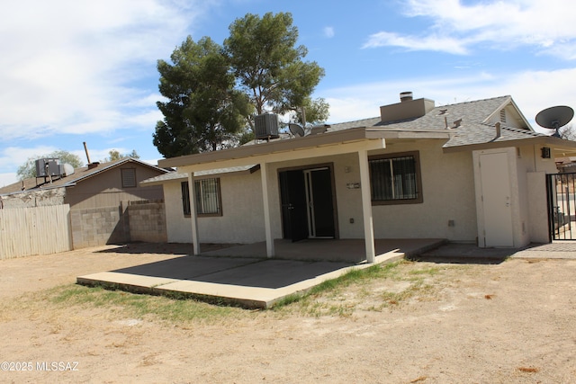 rear view of house featuring fence, central AC, stucco siding, a chimney, and a patio