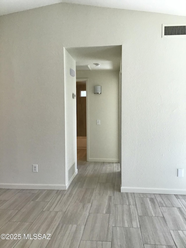 spare room featuring vaulted ceiling, baseboards, and visible vents