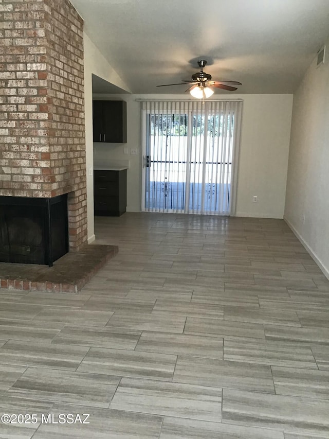 unfurnished living room featuring visible vents, lofted ceiling, a brick fireplace, and a ceiling fan