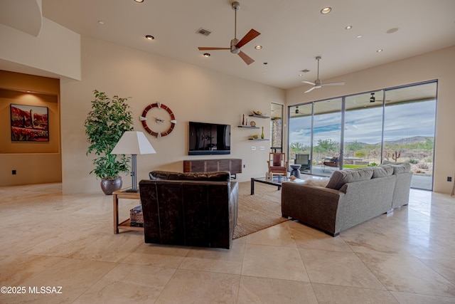 living area featuring a ceiling fan, recessed lighting, and a towering ceiling