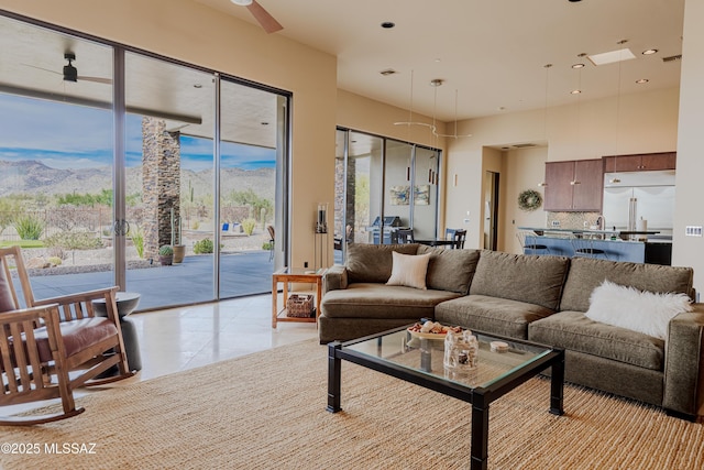 living room featuring light tile patterned flooring, a ceiling fan, and a mountain view