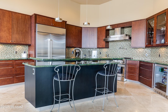 kitchen featuring a kitchen breakfast bar, wine cooler, wall chimney exhaust hood, high end appliances, and a towering ceiling