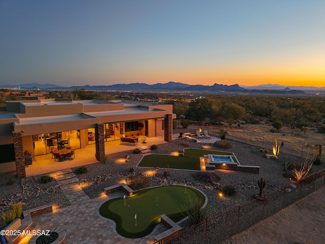 exterior space featuring a mountain view, fence, a fire pit, and a patio area