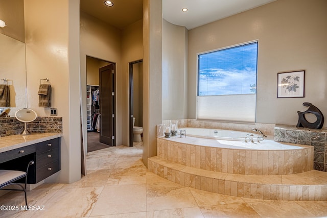 bathroom featuring toilet, recessed lighting, vanity, a bath, and a spacious closet