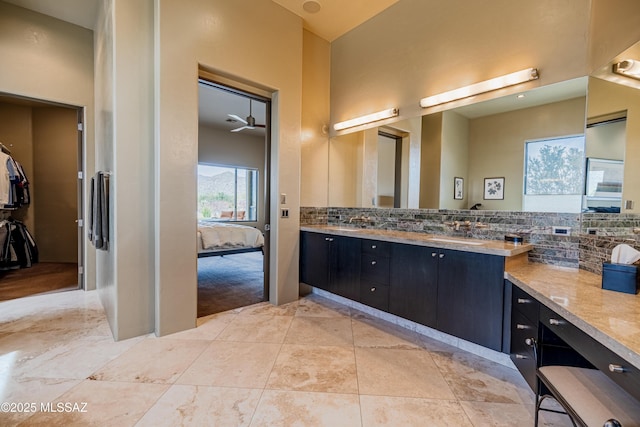 full bathroom with double vanity, a sink, tile patterned flooring, backsplash, and connected bathroom