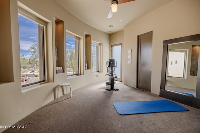 exercise room featuring visible vents, light carpet, and ceiling fan