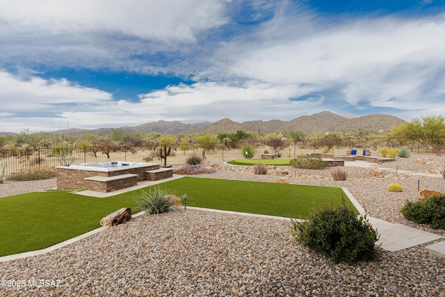 view of yard with a patio area, an outdoor hot tub, a fenced backyard, and a mountain view