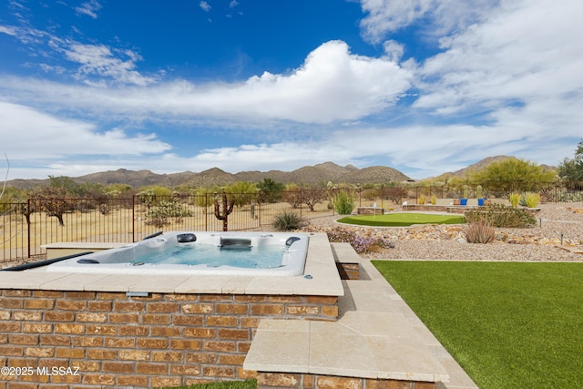 view of swimming pool featuring an outdoor hot tub, a fenced backyard, and a mountain view