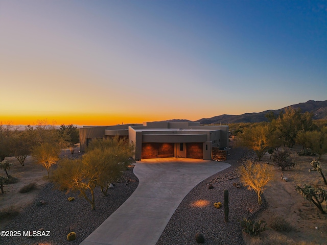 view of front facade featuring an attached garage, a mountain view, driveway, and stucco siding