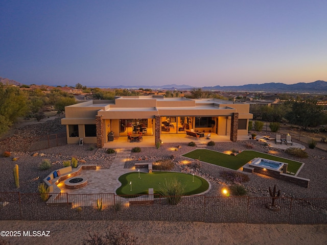 rear view of property featuring a mountain view, a patio, a fire pit, and a fenced backyard