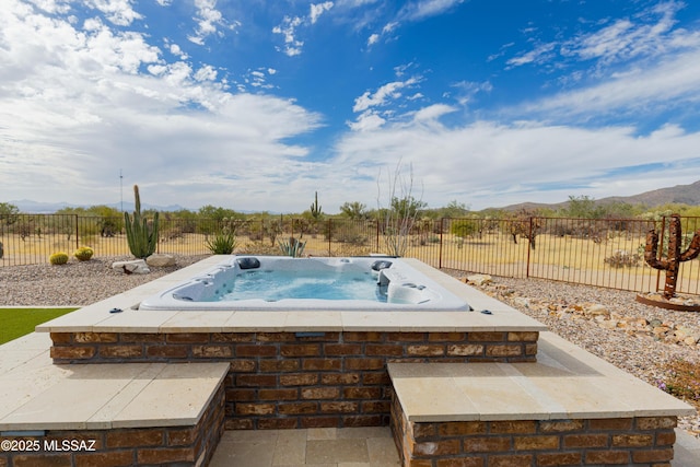 exterior space featuring a mountain view, an outdoor hot tub, and fence