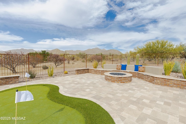 view of patio featuring a fenced backyard, a mountain view, and a fire pit