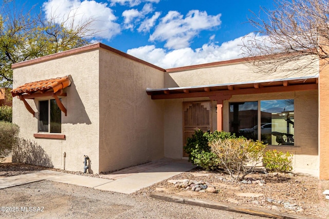 exterior space with a tile roof and stucco siding