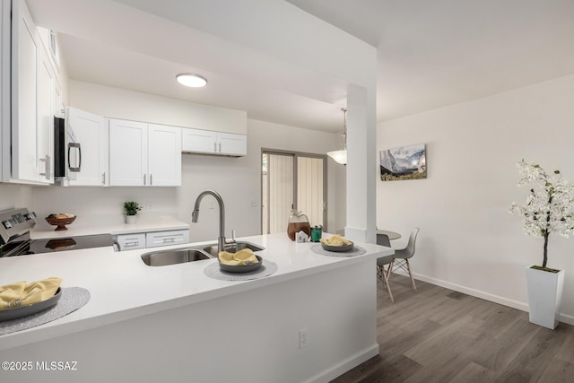 kitchen featuring a peninsula, appliances with stainless steel finishes, light countertops, and a sink