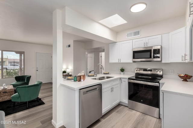 kitchen featuring stainless steel appliances, light countertops, visible vents, white cabinets, and a sink