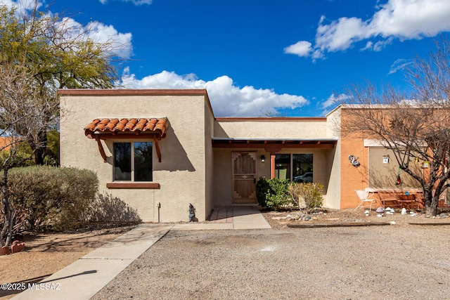 southwest-style home featuring a tiled roof and stucco siding