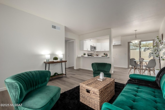 living area featuring light wood-type flooring, visible vents, and baseboards