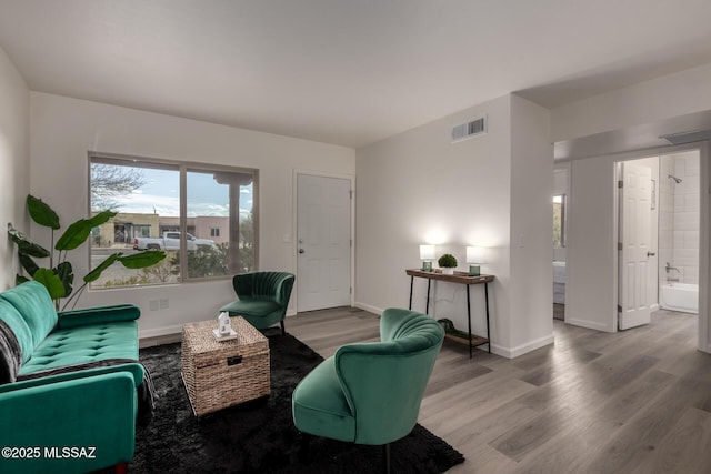 living room featuring baseboards, visible vents, and wood finished floors