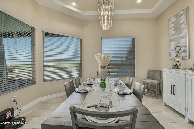 dining area with light tile patterned floors, a tray ceiling, baseboards, and a notable chandelier