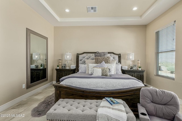 bedroom with a tray ceiling, visible vents, baseboards, and light tile patterned floors