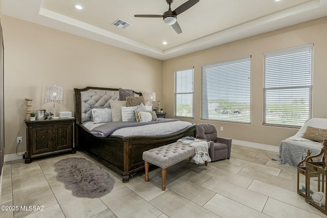 bedroom featuring a tray ceiling, multiple windows, visible vents, and baseboards