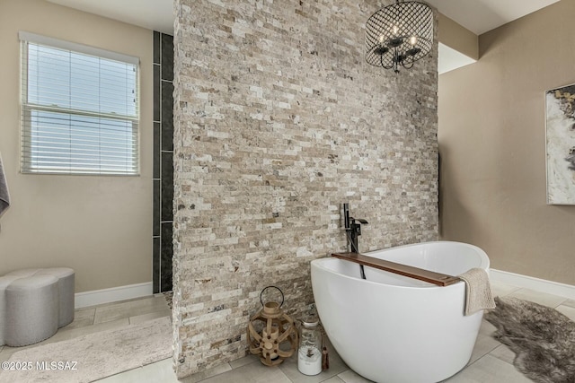 bathroom with baseboards, a freestanding tub, and tile patterned floors